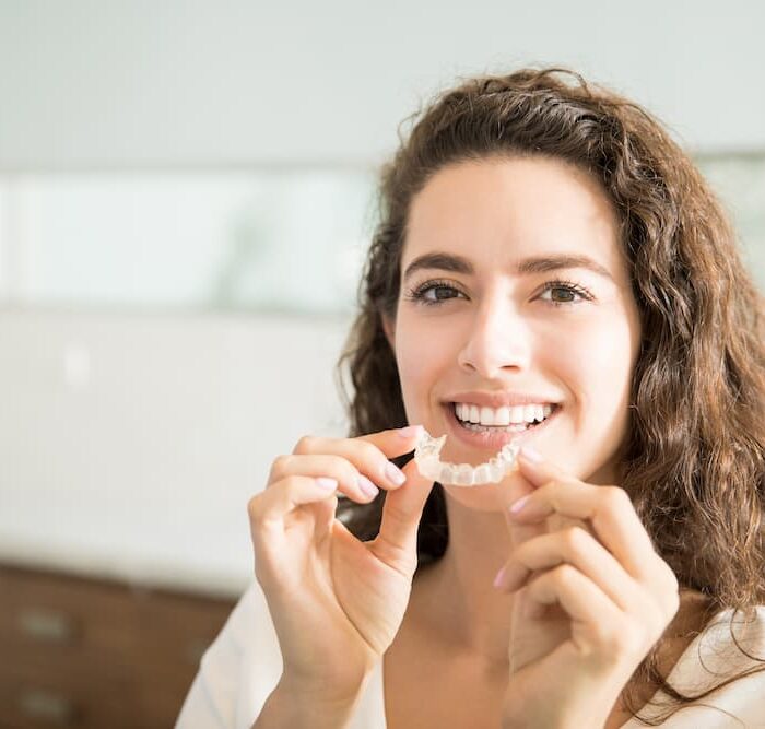 portrait-beautiful-patient-holding-orthodontic-retainers-dental-clinic (1)